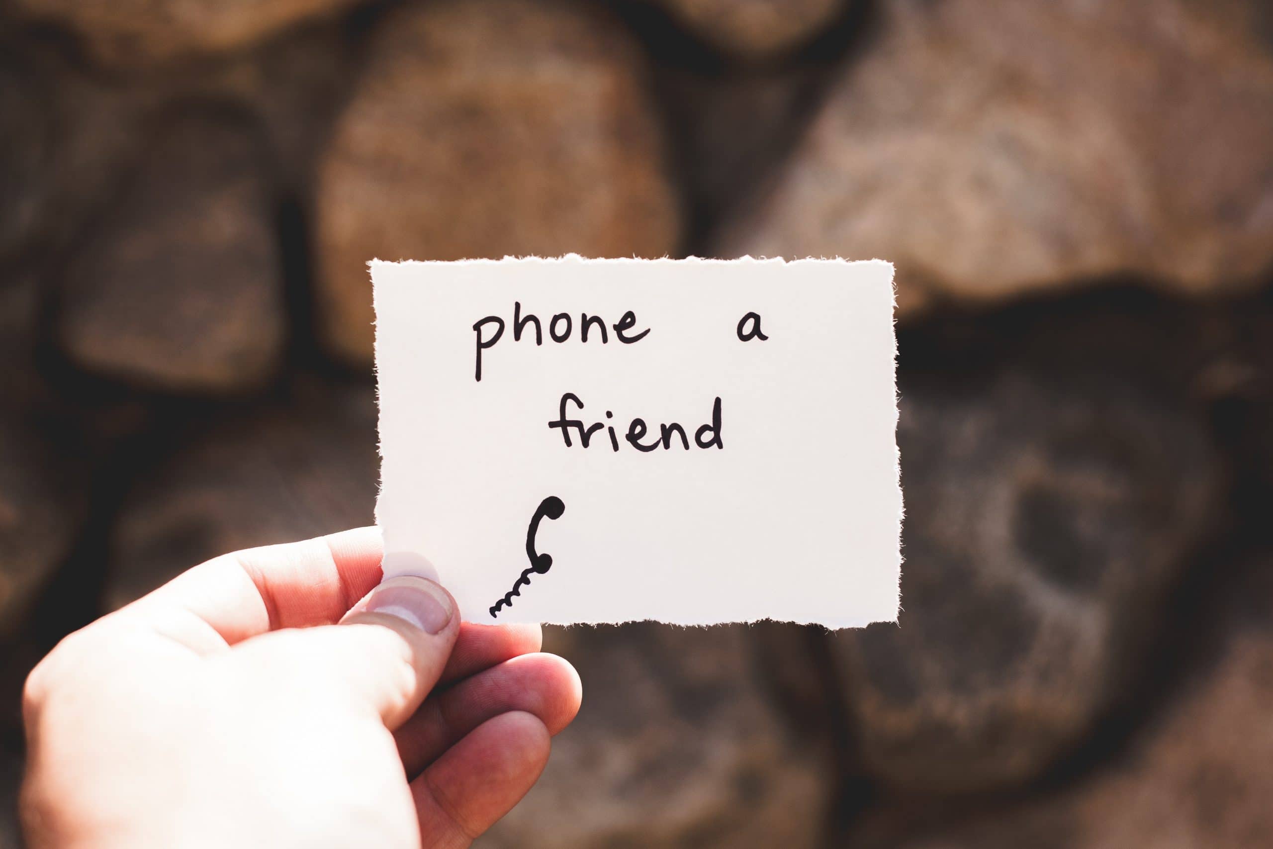 Person holding piece of paper with “phone a friend” written on it